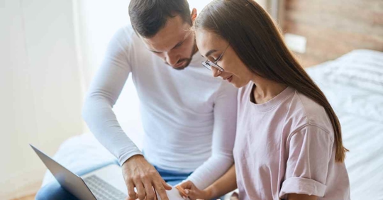 A man and woman sitting next to each other looking at a computer